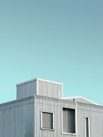 Sleek aluminum-steel shutters on a contemporary house exterior under clear blue sky.