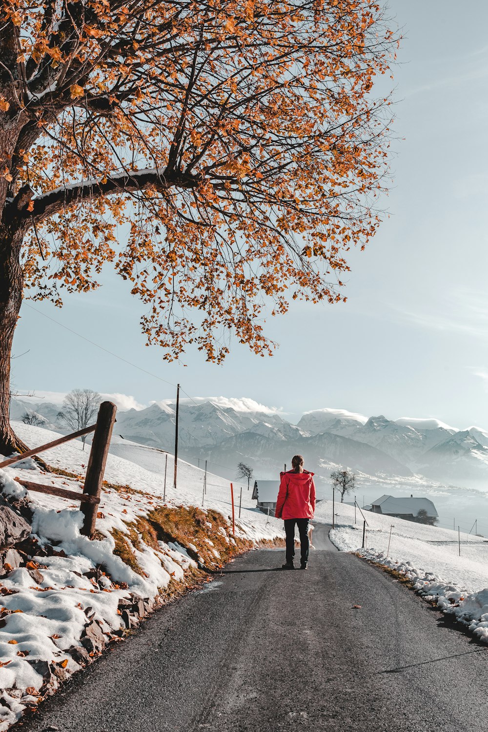 photo of person walking on road wearing red jacket