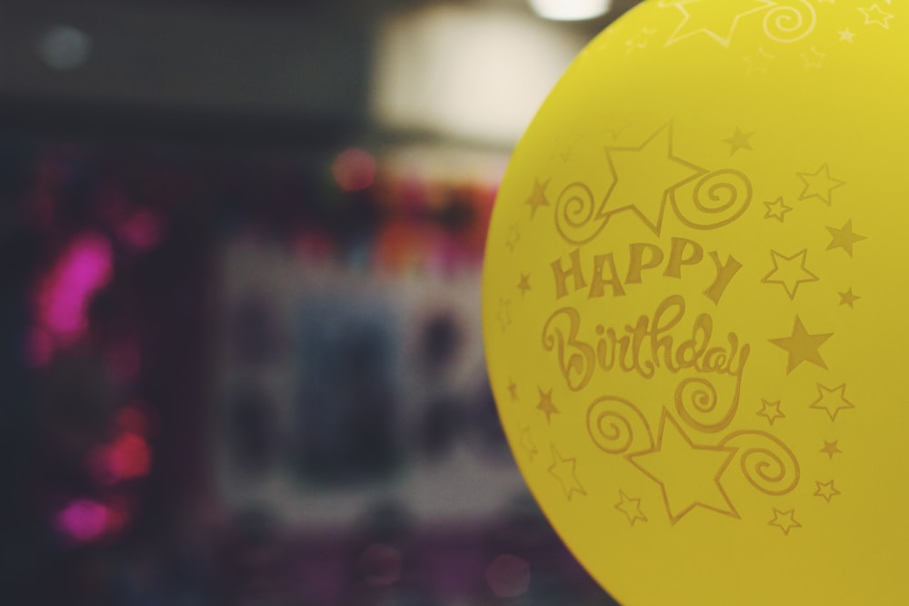 shallow focus photography of yellow happy birthday-printed balloon