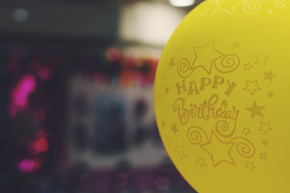 Fotografia de foco raso do balão amarelo impresso de feliz aniversário