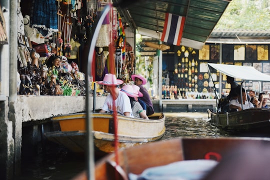 group of people riding wooden boat on water in Damnoen Saduak Floating Market Thailand