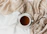 Close-up of a steaming cup of white tea on a beige linen cloth with soft gold accents.