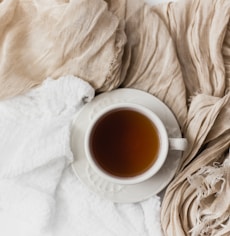 tea filled white ceramic mug on white ceramic saucer