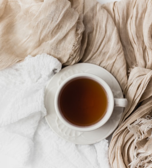 tea filled white ceramic mug on white ceramic saucer