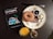 A table setting includes a travel guidebook for Los Angeles, a plate with a sesame bagel, small bowls of butter and jam, a croissant piece, a glass of orange juice, and a small jar of granola.