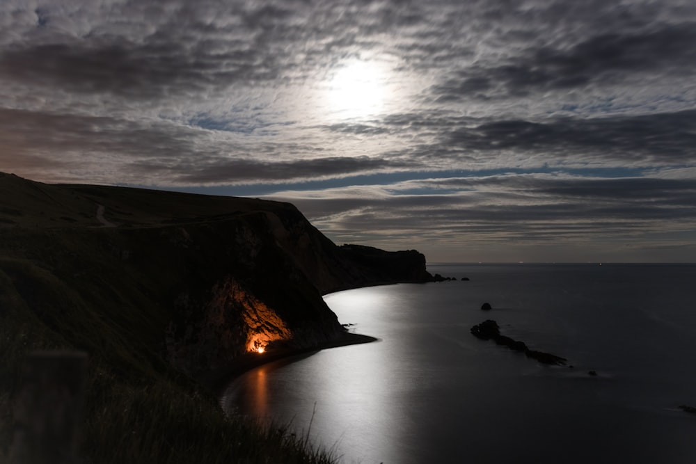 Fotografia de paisagem do penhasco sob o céu cinzento durante a noite