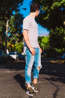 Casual streetwear outfit featuring a bold graphic tee and distressed jeans on a sunny sidewalk