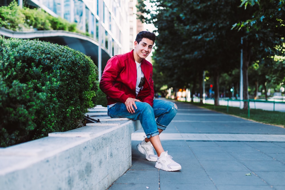 shallow focus photography of man sitting on pavement while smiling