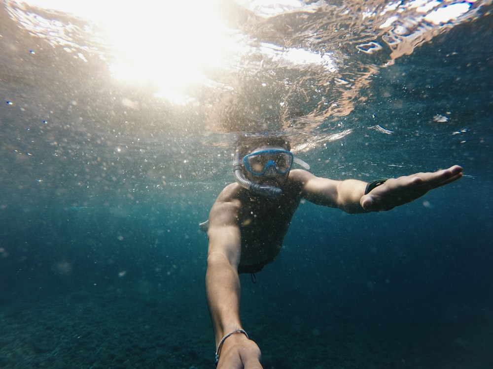 man swimming underwater with goggles