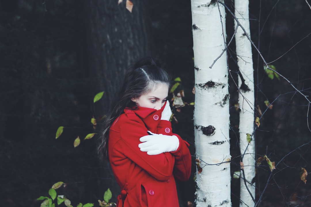 close-up photography of woman covering mouth by red apparel