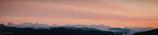 A panoramic view of a bear silhouetted against a vibrant sunset.