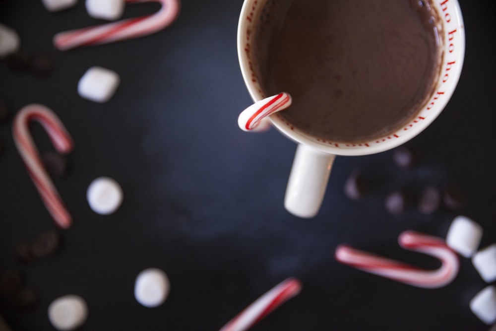 Caneca de cerâmica branca com chocolate e cana de bala