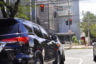 An executive SUV with tinted windows waiting curbside at O'Hare International Airport under bright daylight.