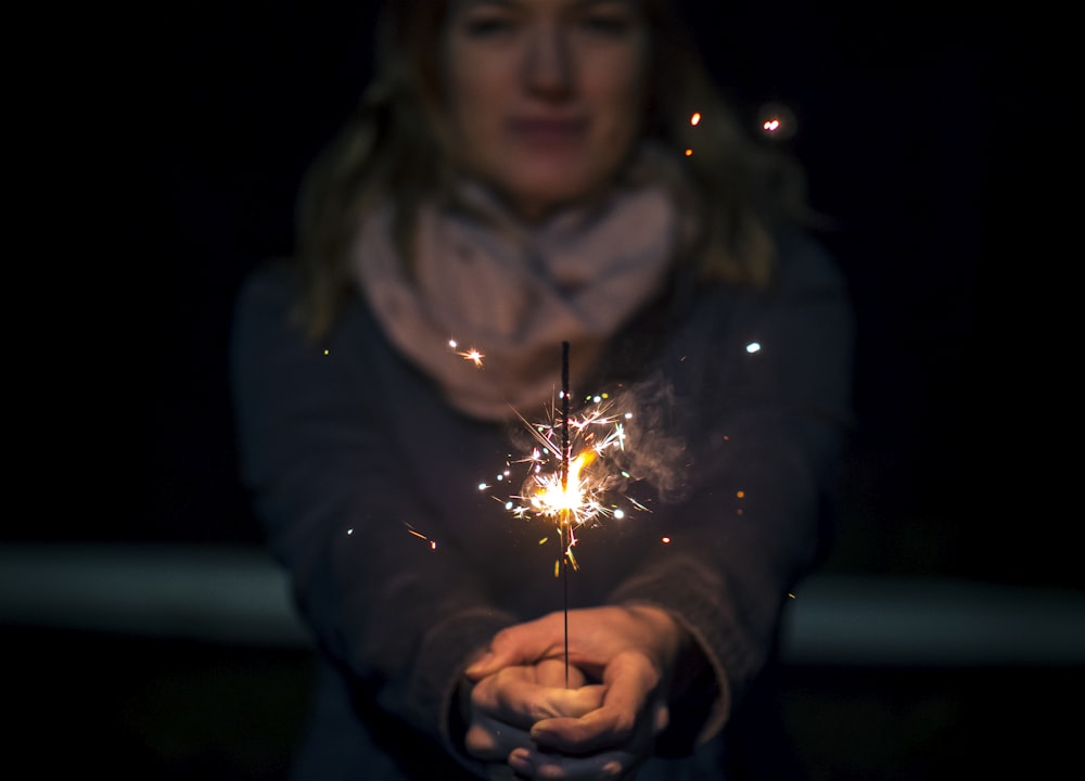 woman holding sparkler during night