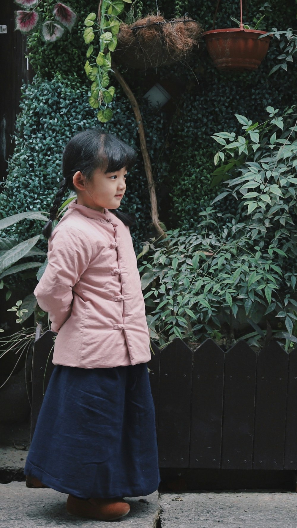 植物の近くでピンクのジャケットを着た女の子