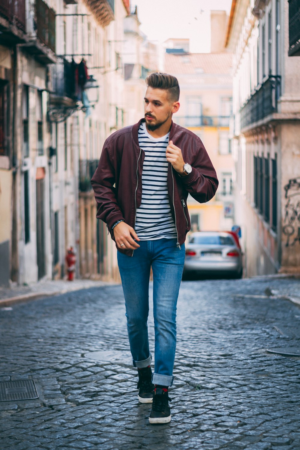 man in maroon zip-up jacket walking near building