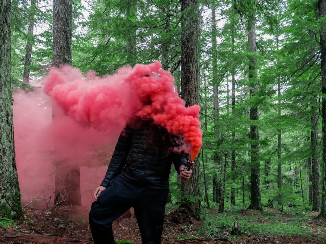 person holding smoke grenade with red color smoke