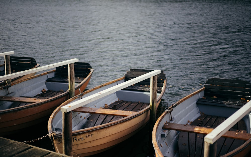 thee brown wooden boats beside dock with body of water during daytime