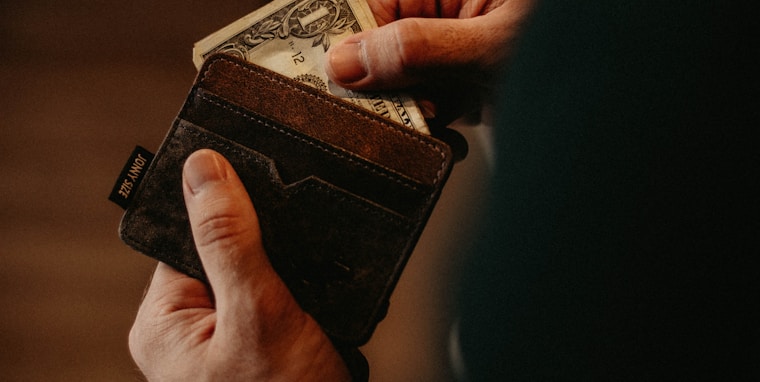person getting 1 U.S. dollar banknote in wallet