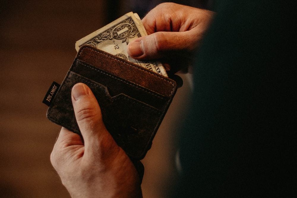 財布に 1 米ドルの紙幣を入れる人