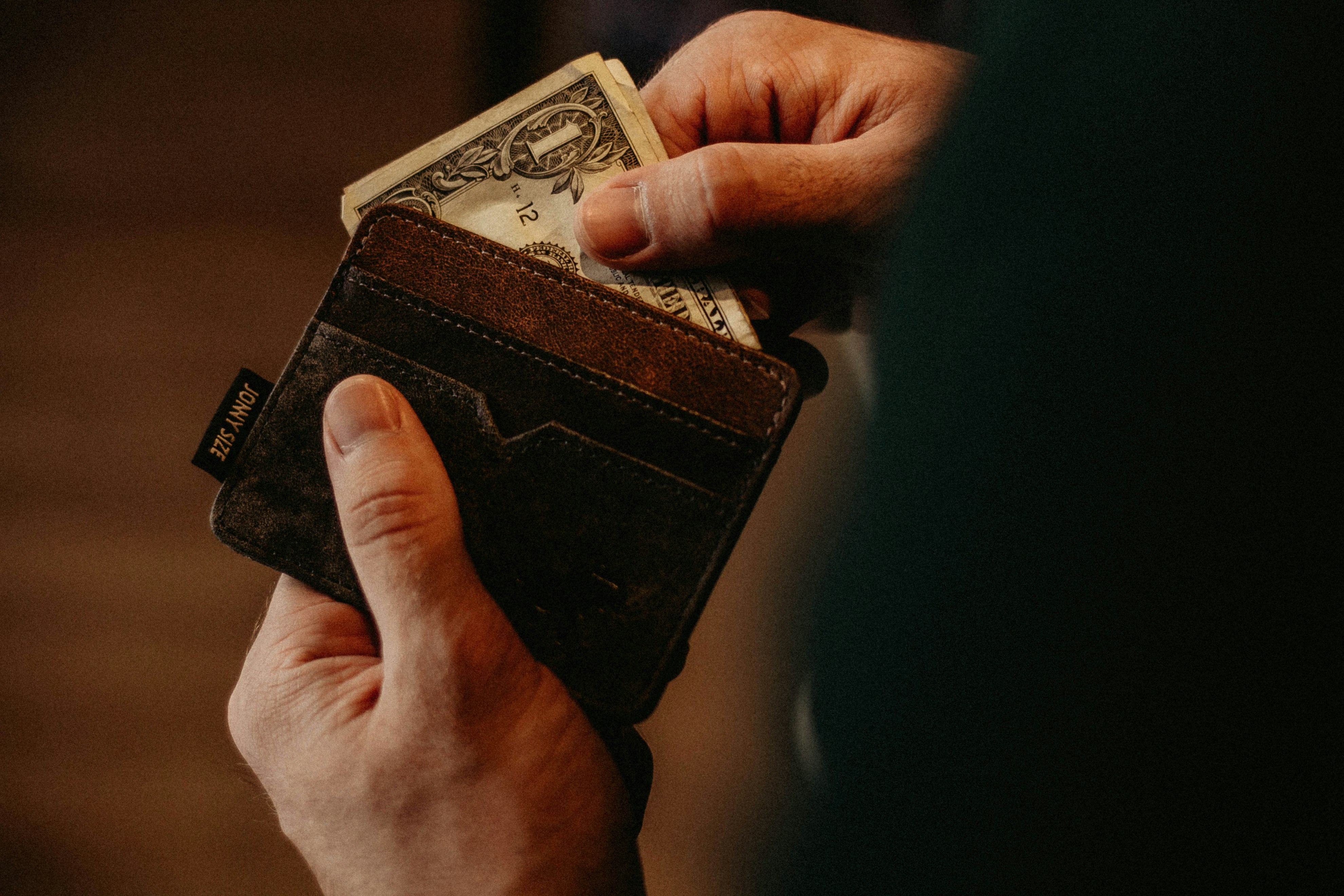 A person holding a wallet with money in it.