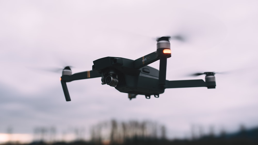 black quadcopter drone hovering in the air