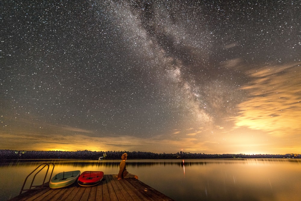 person sitting on dock looking at body of water