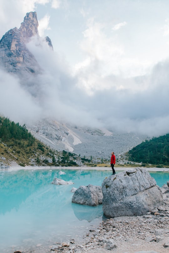 man standing on top of gray rock near body of water in Sorapiss Italy