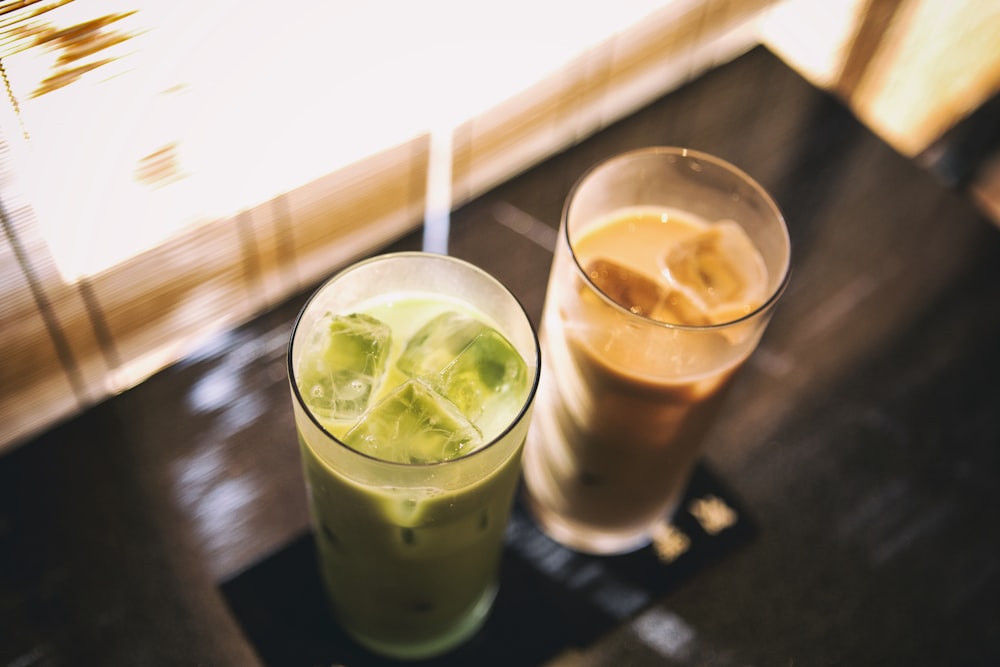 two glass cups with cold beverage inside