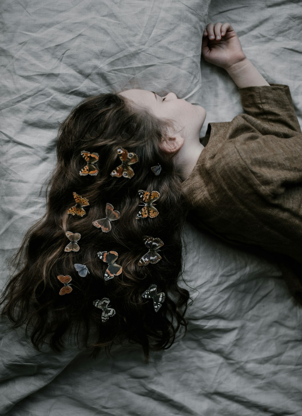 girl lying on gray bed sheet