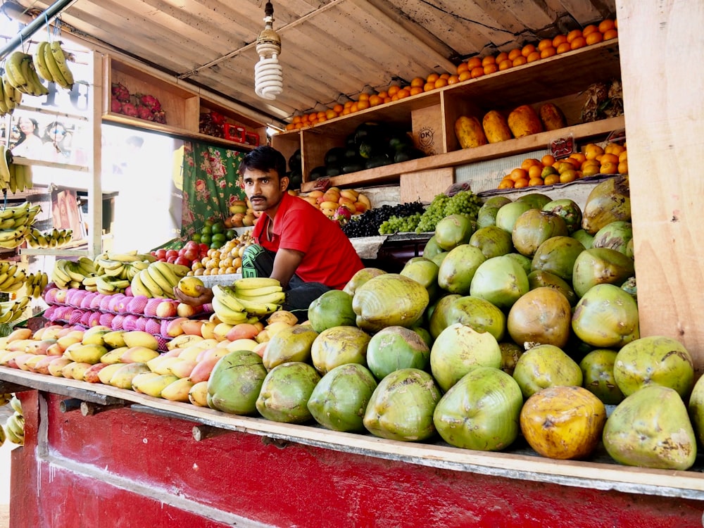 um homem parado em frente a uma banca de frutas