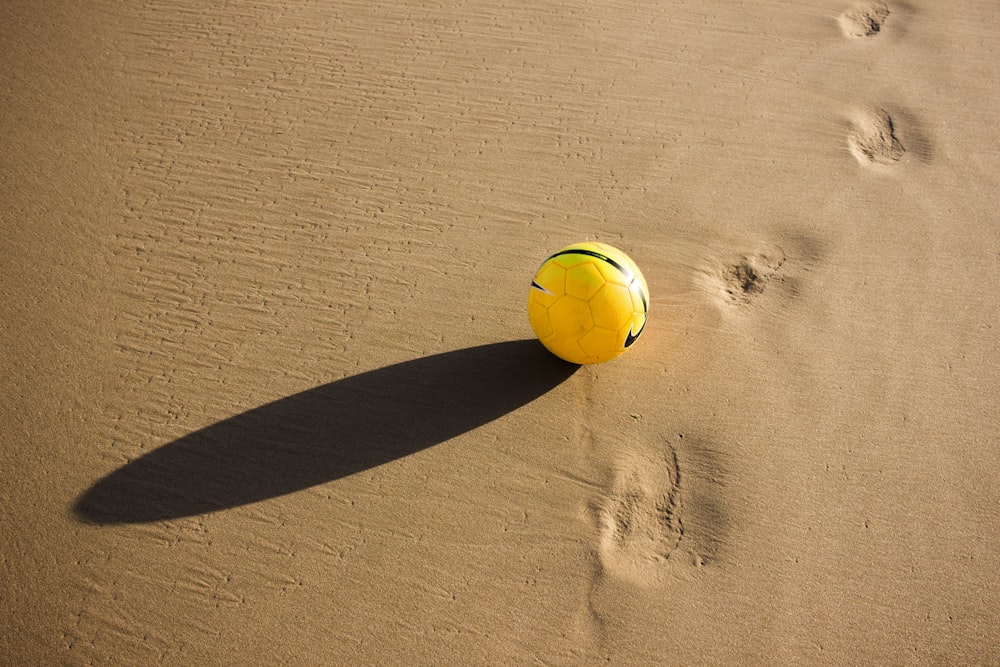 Balón de fútbol amarillo y verde en el desierto