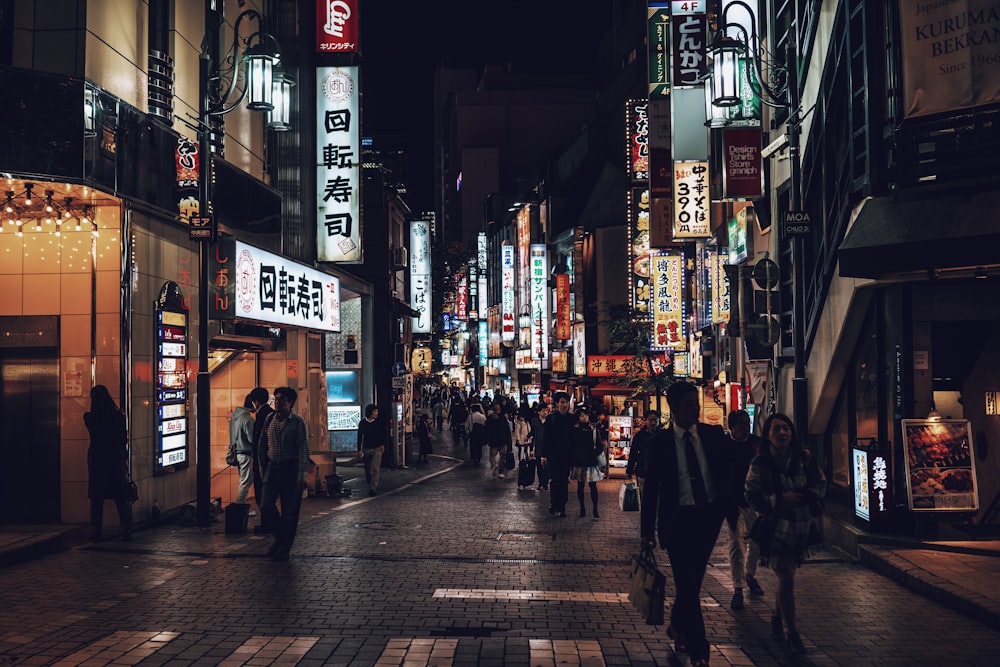 people walking beside building during nighttime