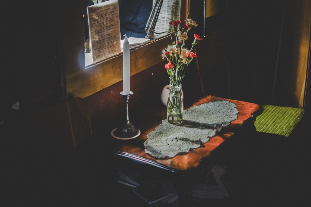 Kerzenständer auf Tischplatte mit Blumenvase