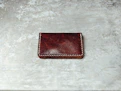 A charcoal grey wallet placed on a warm sand-colored marble surface.
