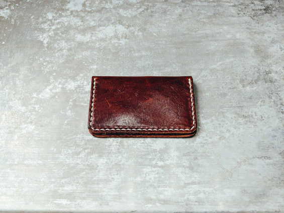 Close-up of a rugged leather wallet with detailed stitching on a wooden table.