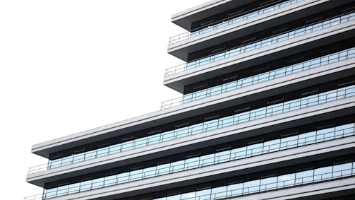 A modern, multi-story building is depicted, showcasing a series of horizontal lines and a sleek, minimalist design with extensive use of glass windows.