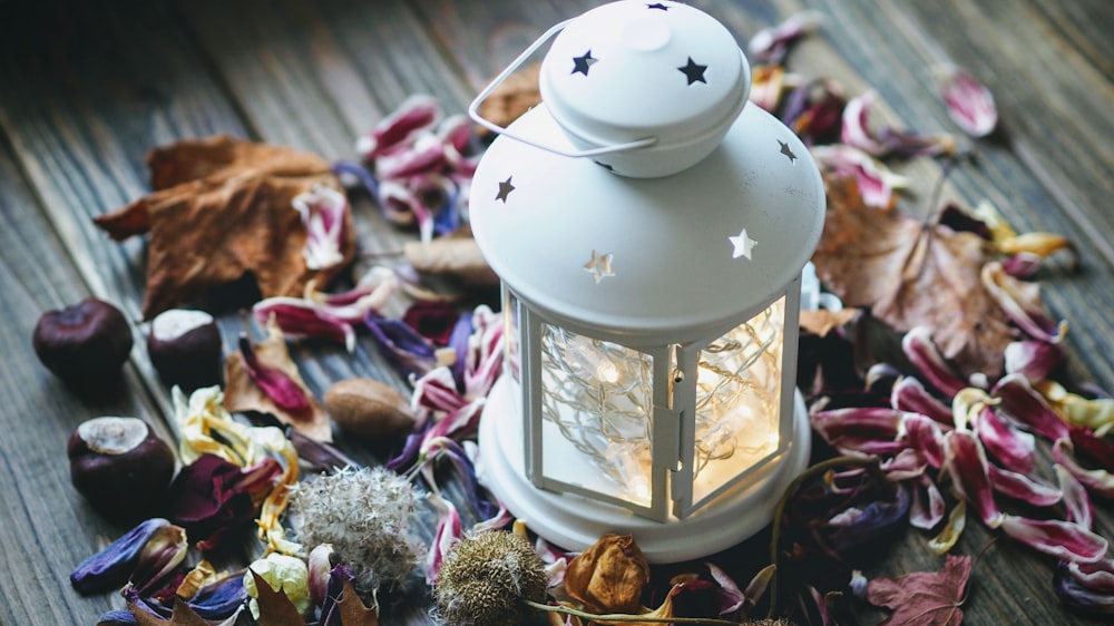 white candle lantern surrounded petals