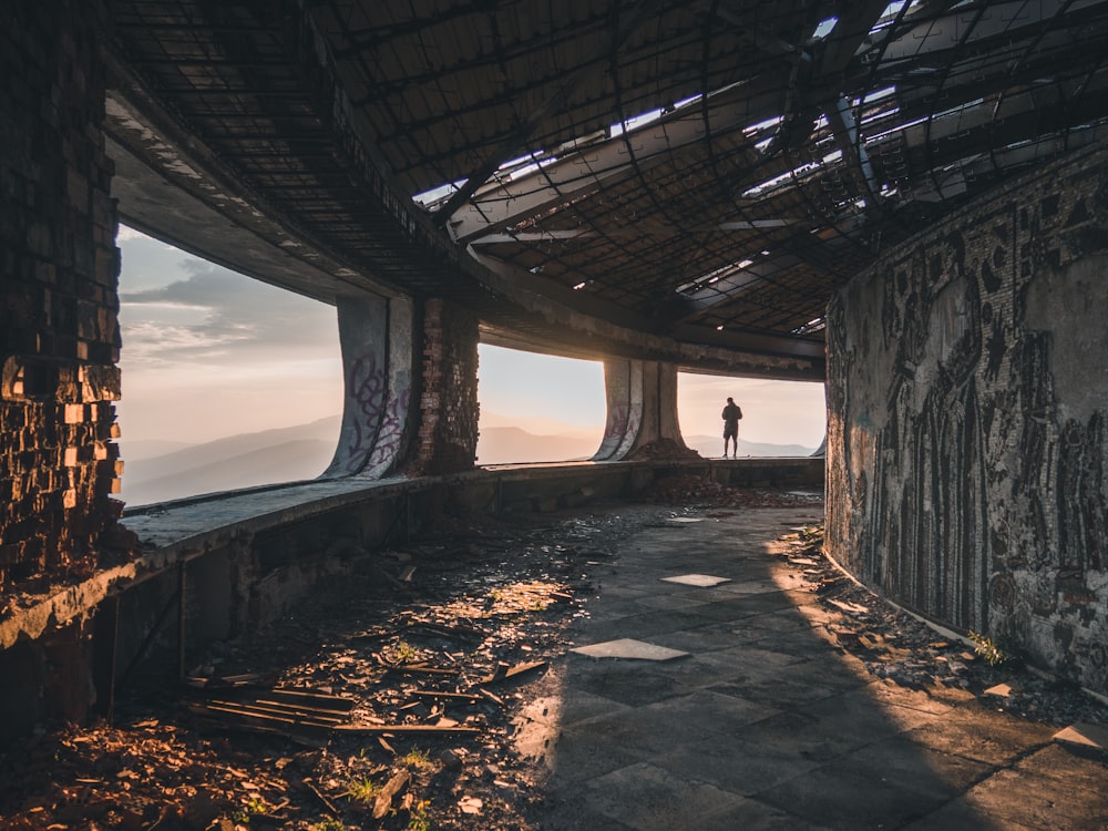 person standing on concrete beam facing mountain