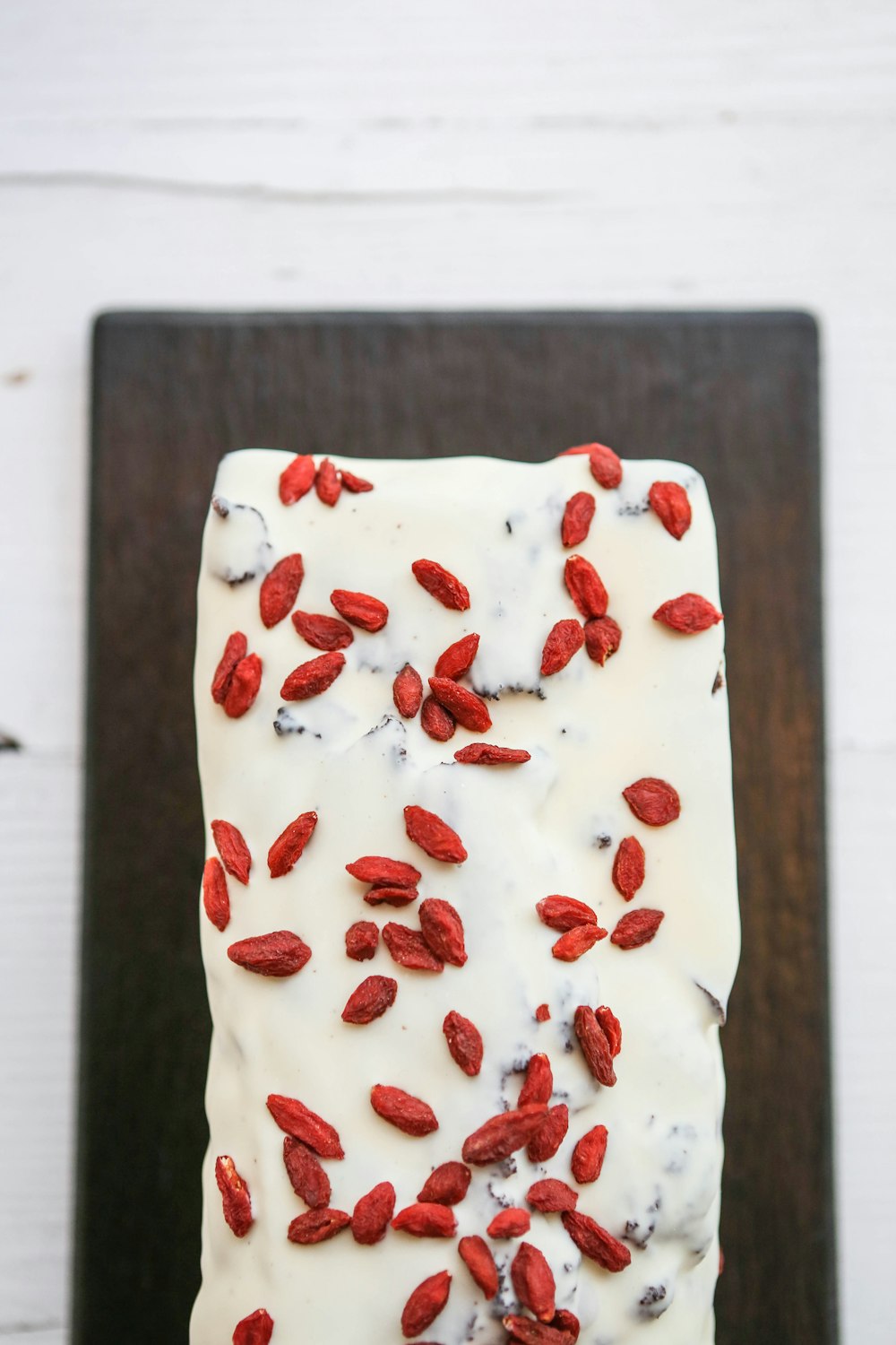 Un pedazo de pastel con glaseado blanco y bayas rojas en la parte superior