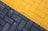 A close-up view of a paved surface with interlocking bricks. The bricks are arranged in two distinct sections; one side is painted yellow and the other is gray, creating a diagonal division.