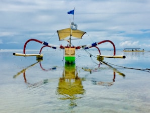 A vibrant Hawaiian canoe cutting through gentle waves near the central beach of Marataízes.