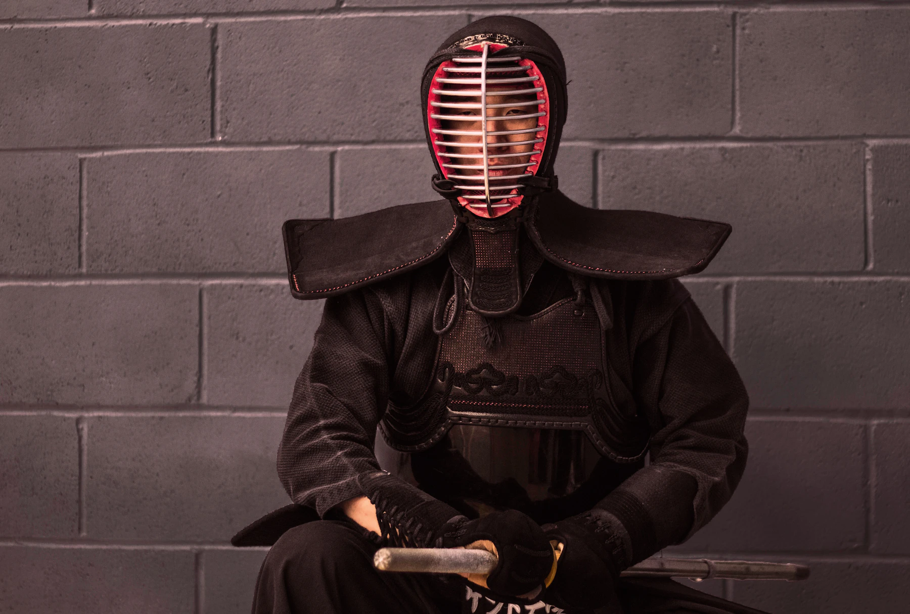 A kendoka in full armour seated with his shinai, waiting to begin