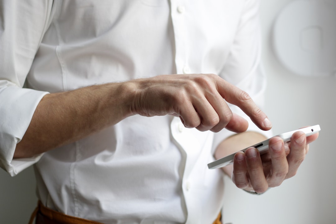 a mobile application developer wearing a white shirt and using a phone