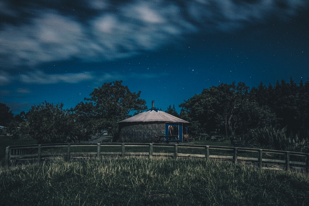夜の白い雲の下の丘の上の茶色の小屋