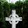 white wooden celtic cross near green leafed plants at daytime