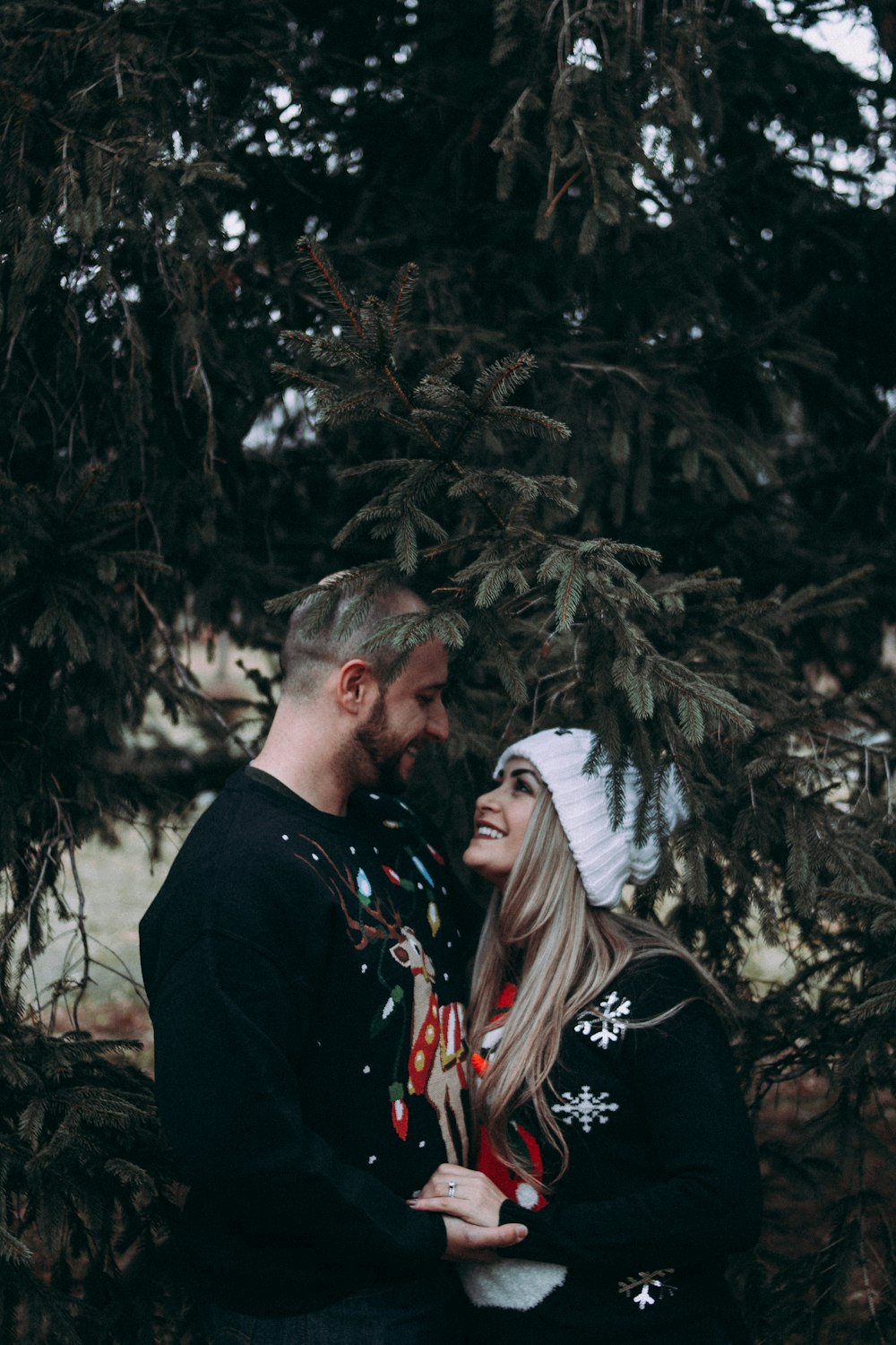 hombre y mujer mirándose el uno al otro de pie bajo un árbol de hojas verdes