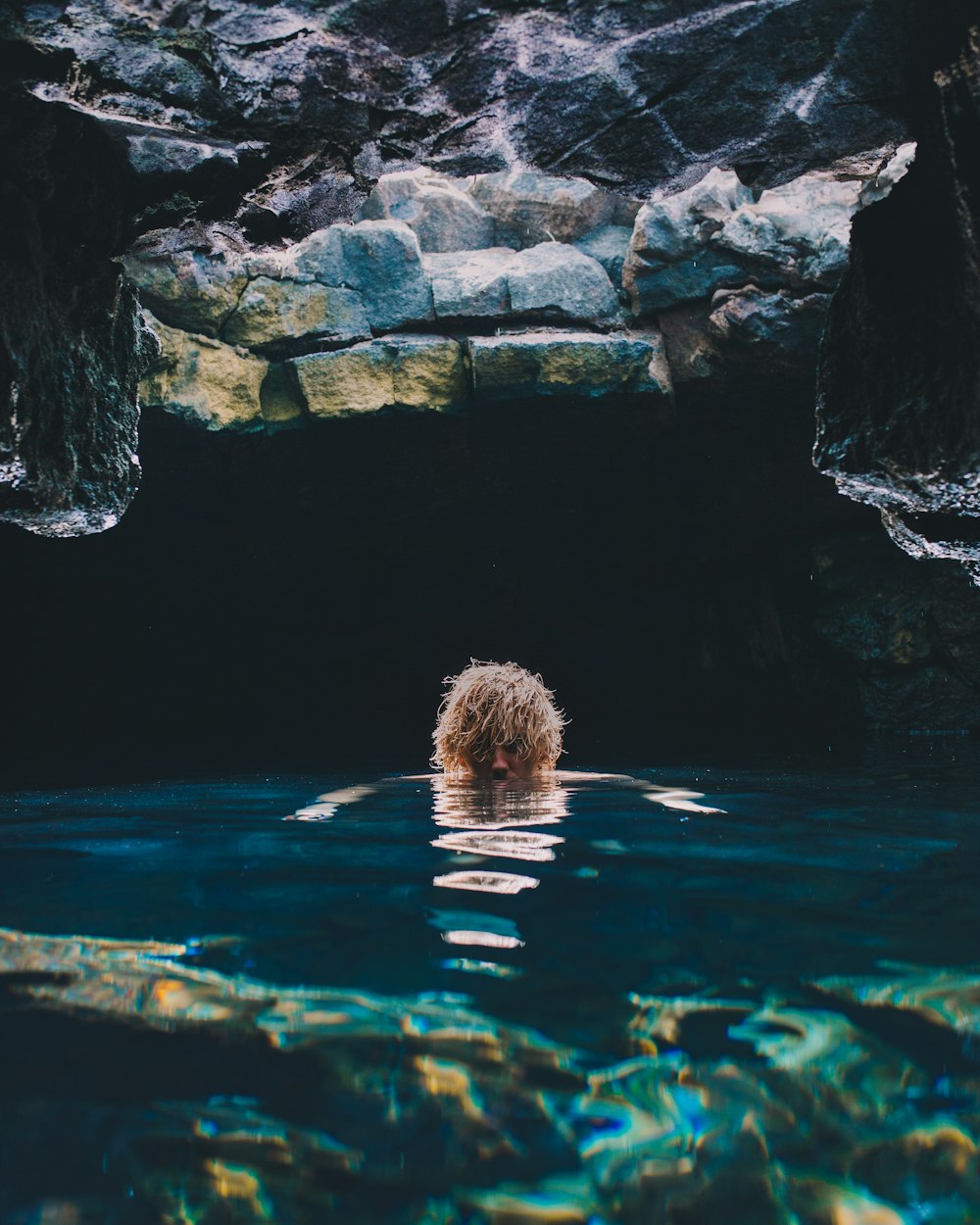 person submerged in water on cave