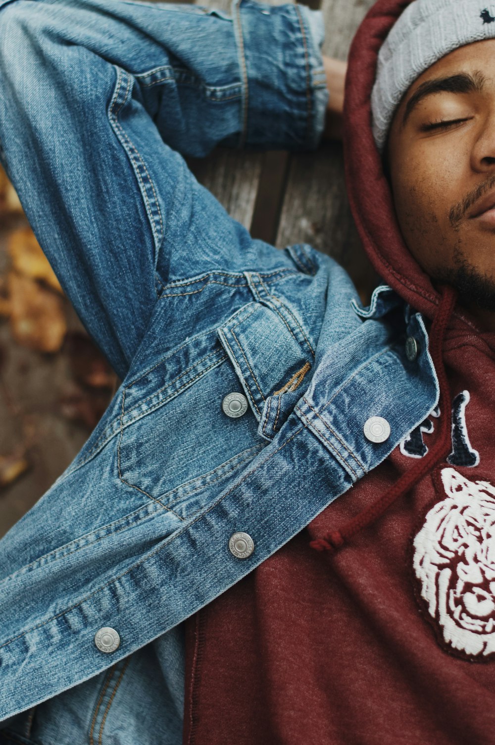 man lying on bench wearing blue denim jacket