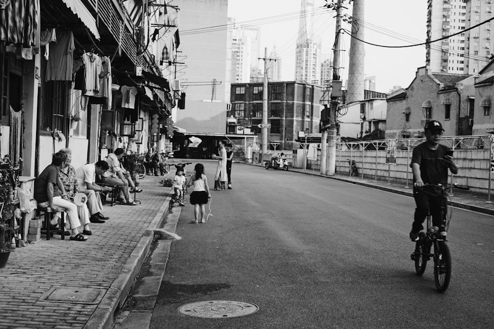 grayscale photograph of person riding bicycle while using smartphone